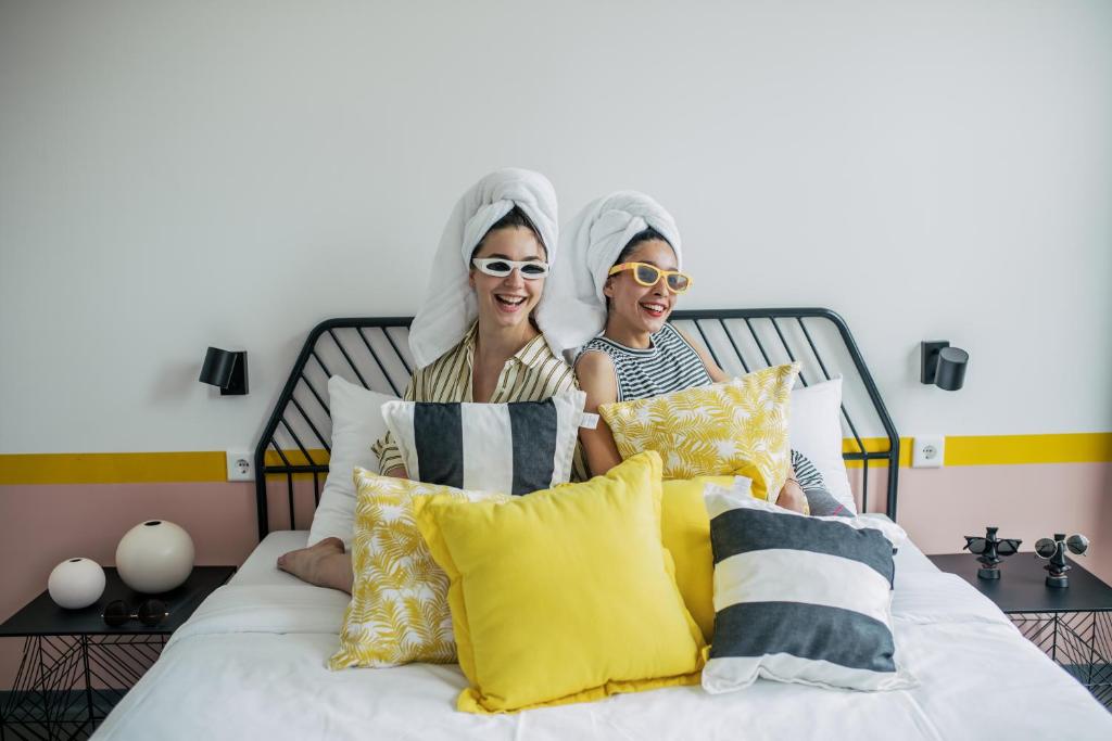 Dos mujeres están sentadas en una cama. en Pink Flamingo Boutique Hostel, en La Haya