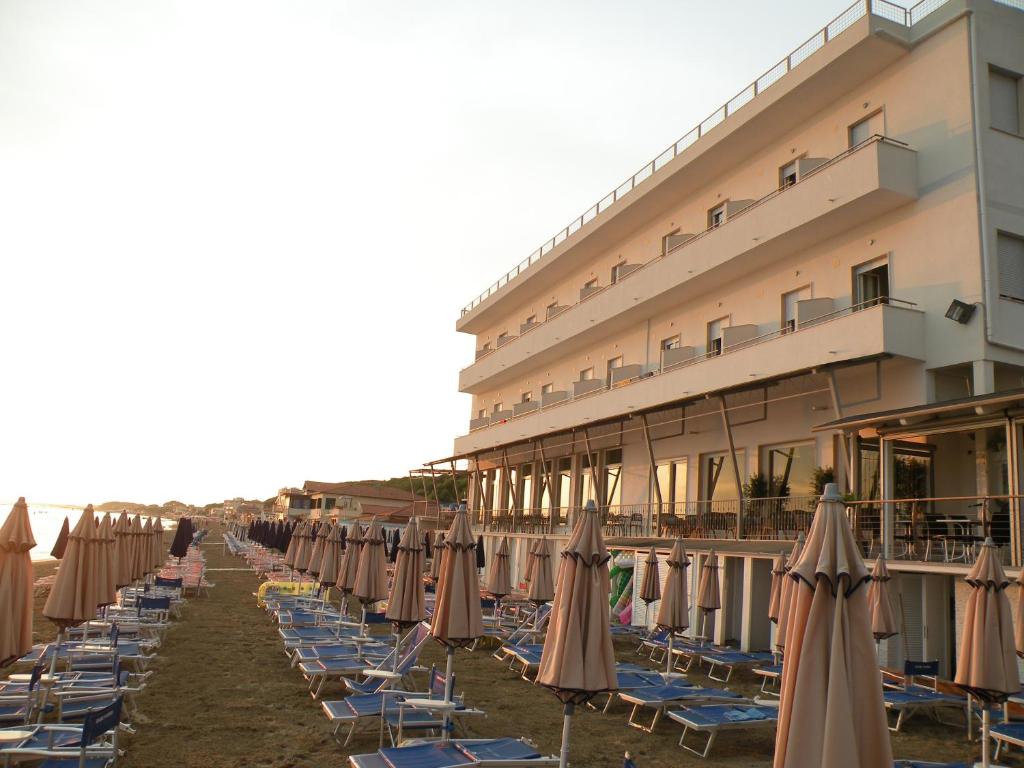 een rij strandstoelen en parasols voor een hotel bij Hotel Parrini in Follonica