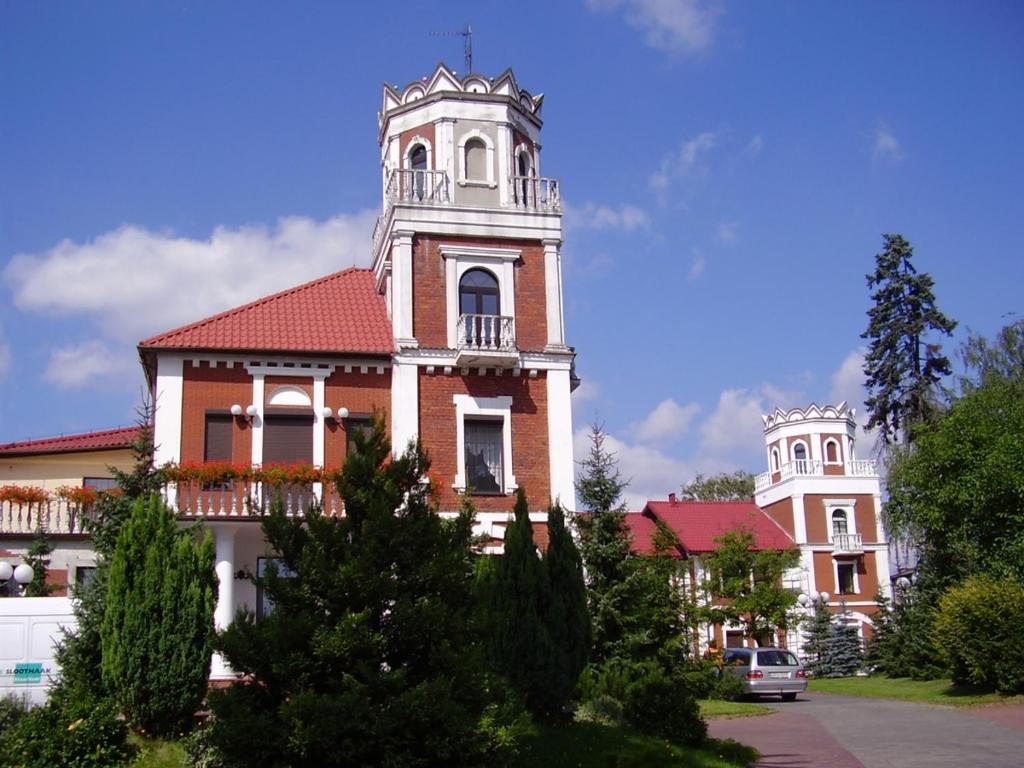 een gebouw met een toren erop bij Hotel Zameczek in Radomsko