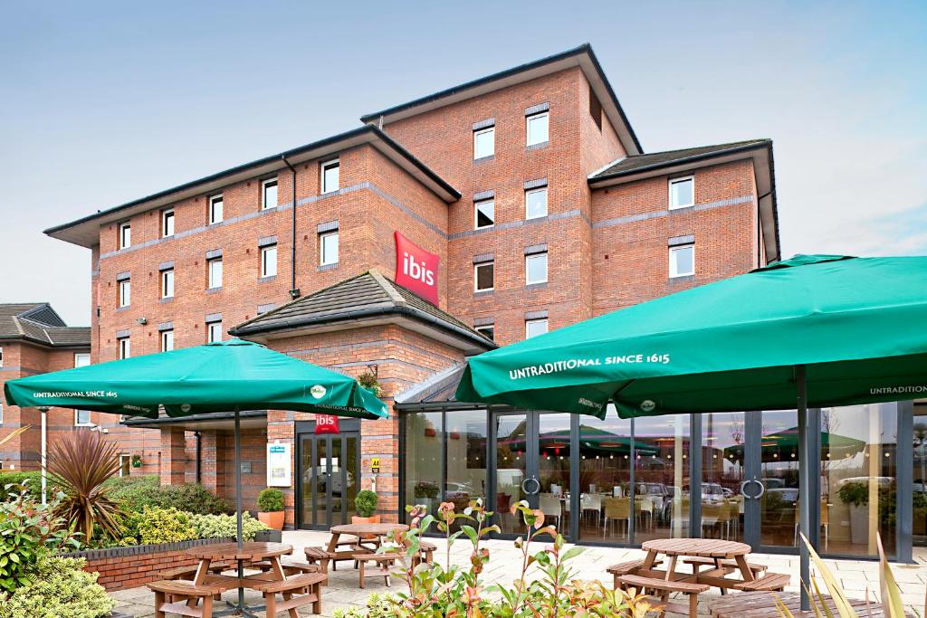 un ristorante con tavoli e ombrelloni di fronte a un edificio di ibis Liverpool Centre Albert Dock – Liverpool One a Liverpool