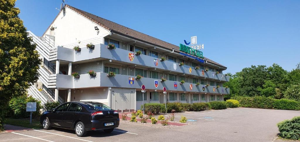 een auto geparkeerd voor een gebouw bij Brit Hotel Confort Nancy Lunéville in Lunéville