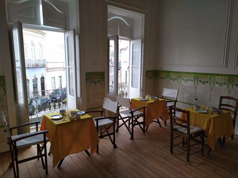 een eetkamer met tafels en stoelen met geel tafelkleed bij OlhãOmirante Guesthouse in Olhão