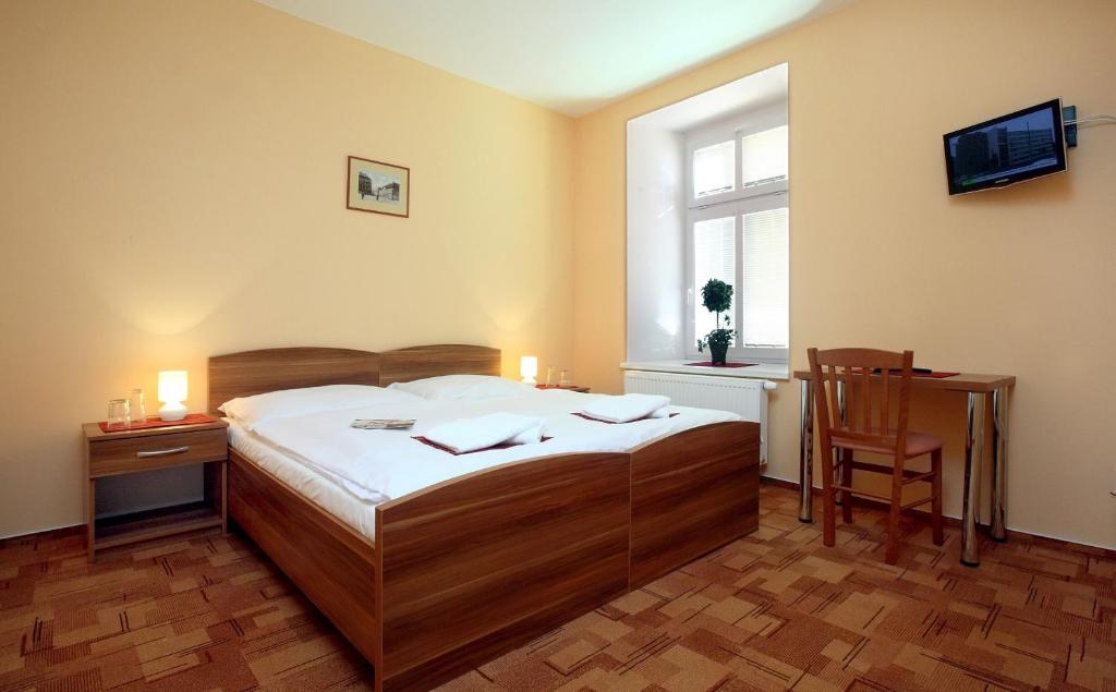 um quarto com uma cama, uma secretária e uma janela em Pension Wallis em Plzeň