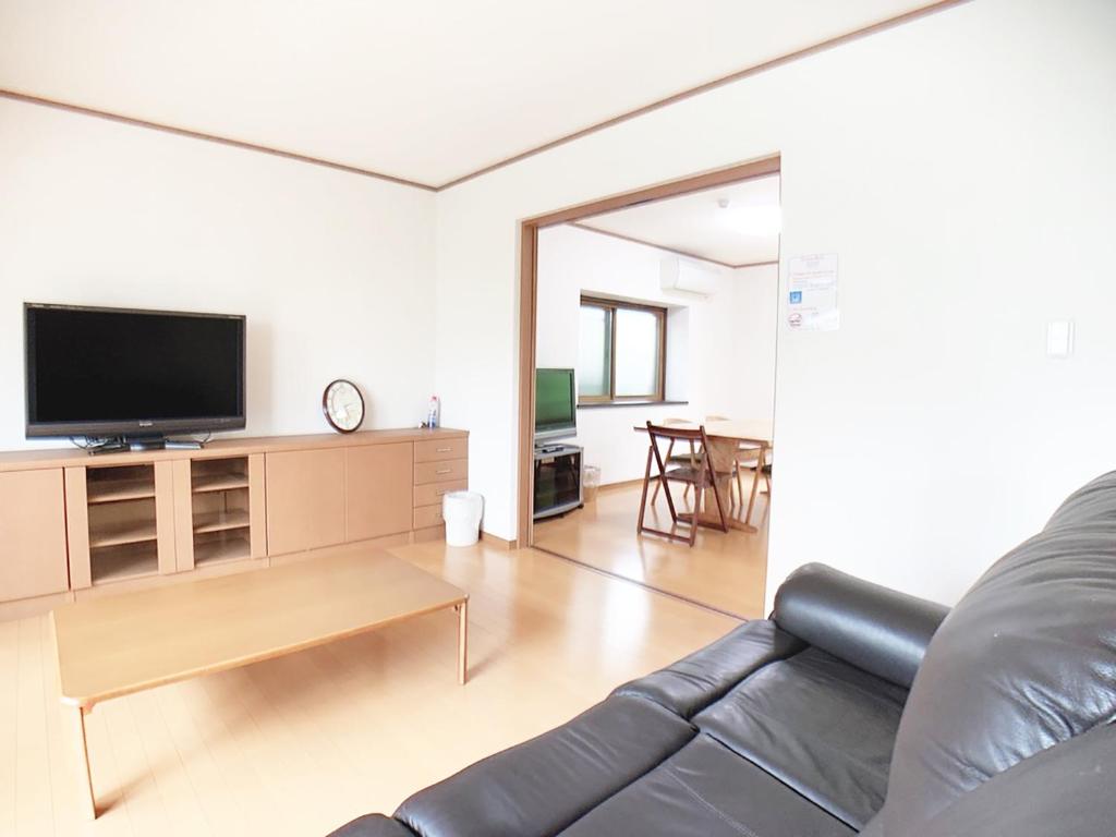 ein Wohnzimmer mit einem Sofa und einem Flachbild-TV in der Unterkunft Itsukaichi First Villa Hiroshima in Hiroshima