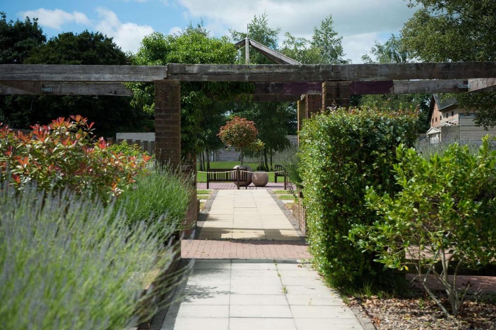 un jardin avec une pergola en bois et quelques buissons dans l'établissement Barton Manor Hotel & Spa; BW Signature Collection, à Preston