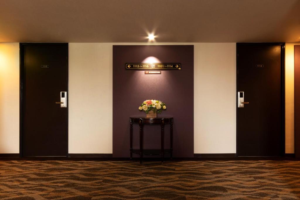 eine Lobby mit drei Türen und einer Vase Blumen auf dem Tisch in der Unterkunft Toyo Hotel in Fukuoka