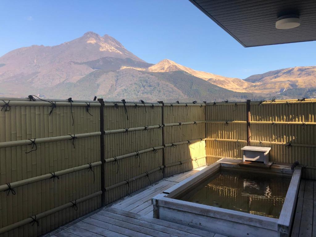 uma piscina de água com montanhas ao fundo em Yufuin Akarinoyado em Yufu