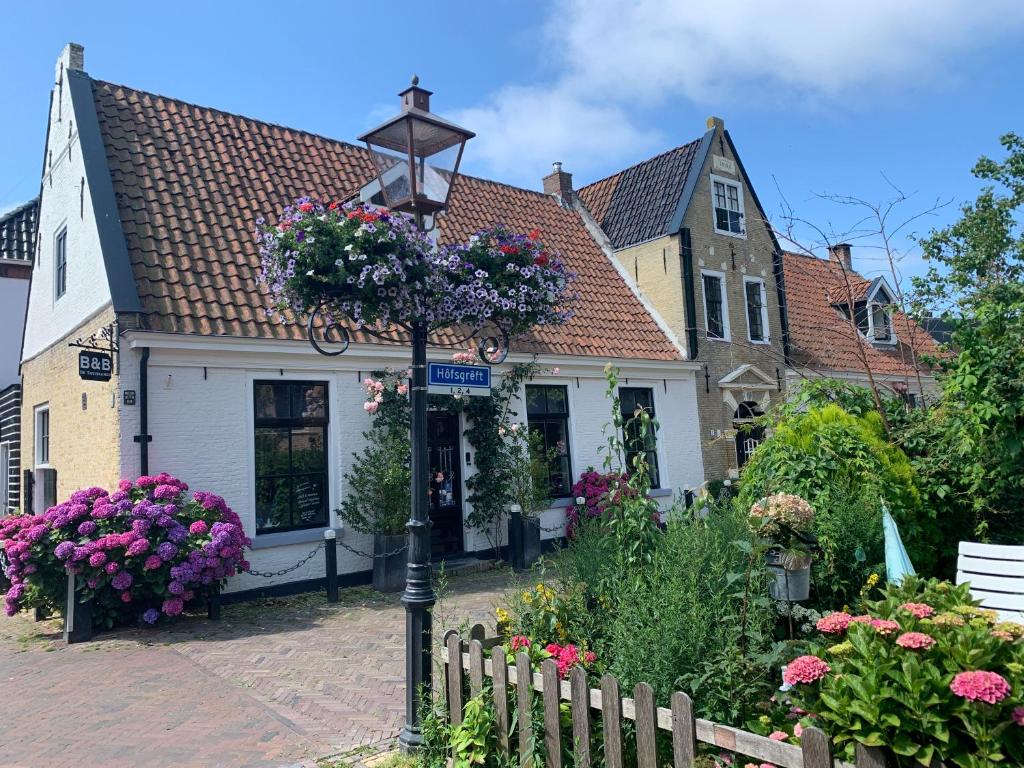 uma luz de rua em frente a uma casa com flores em De Thuiskamer in Grou als B&B of Vakantiehuis em Grou