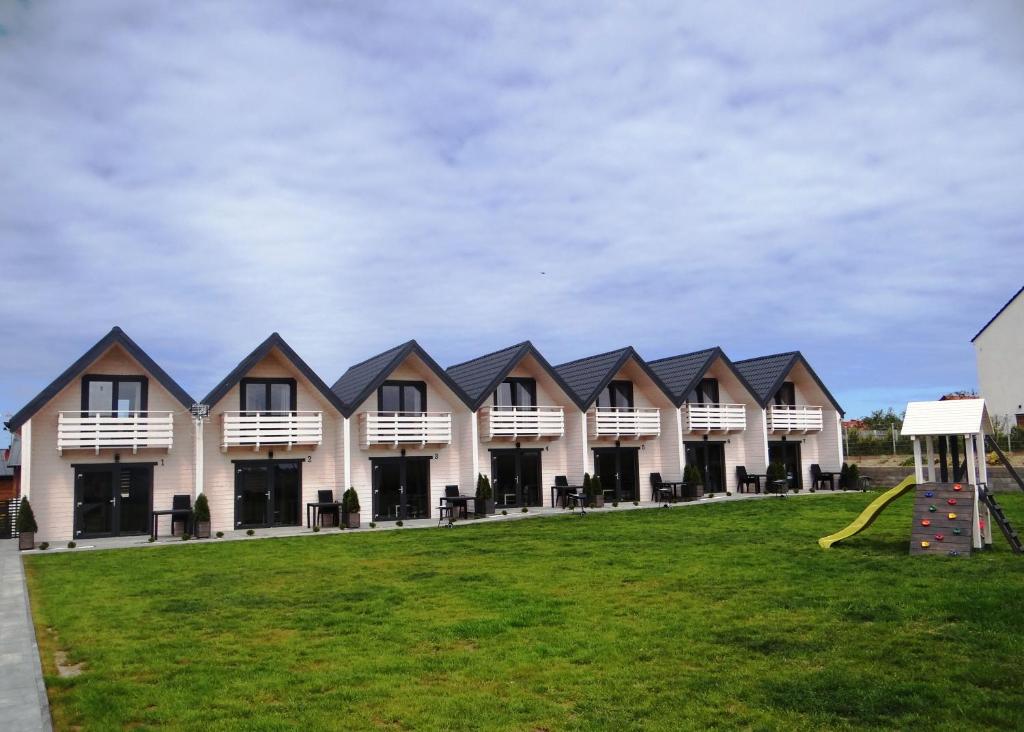 eine Reihe von Häusern mit Spielplatz im Gras in der Unterkunft White Houses Rewal in Rewal