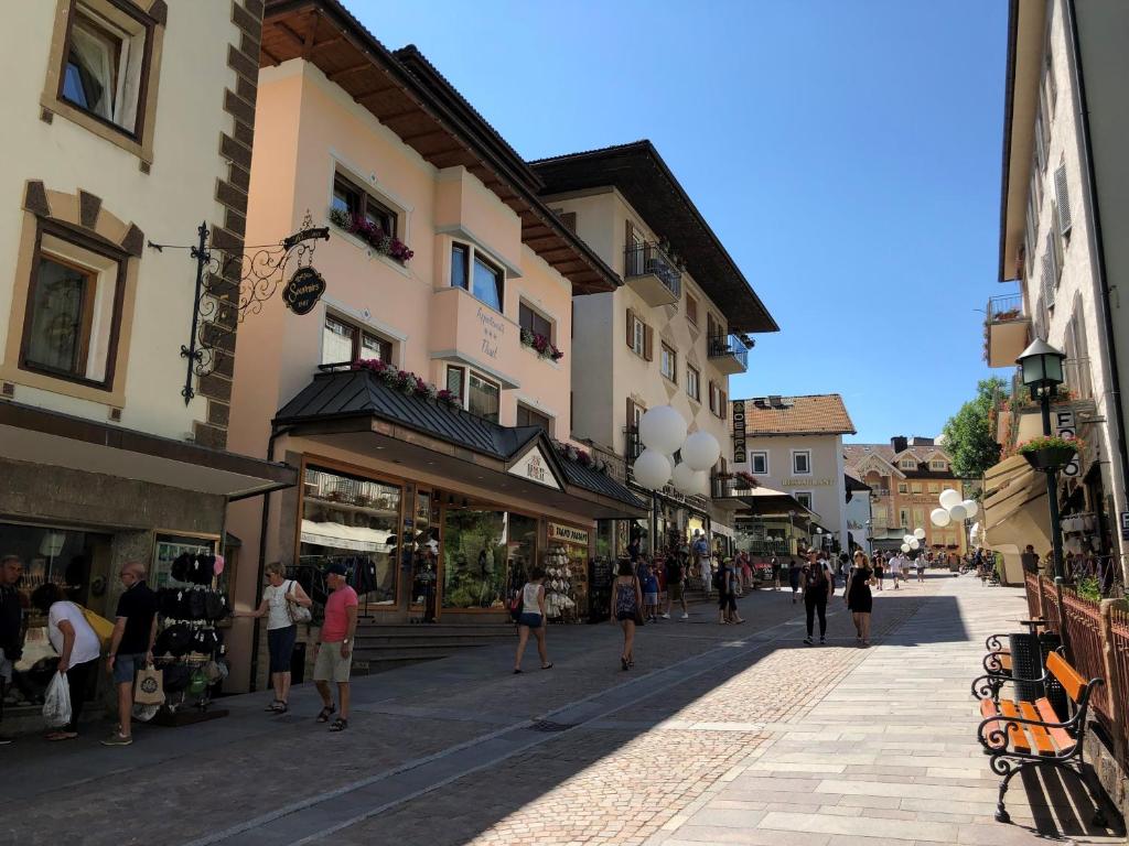 um grupo de pessoas andando por uma rua com edifícios em Appartements Tlusel em Ortisei