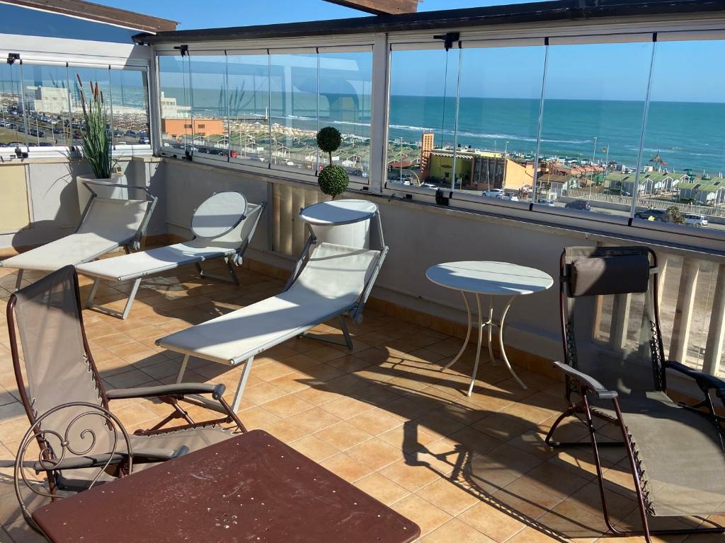 balkon z krzesłami i stołami oraz widokiem na ocean w obiekcie Hotel Bellavista w mieście Lido di Ostia