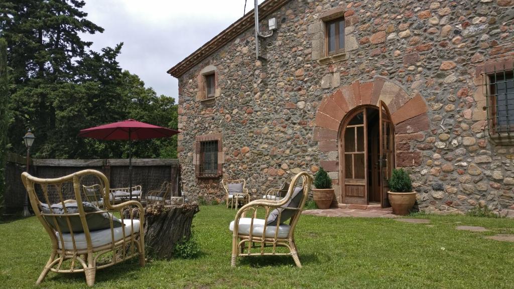 un groupe de chaises et un parasol devant un bâtiment dans l'établissement Masia Can Bachs, à Sant Pere de Vilamajor