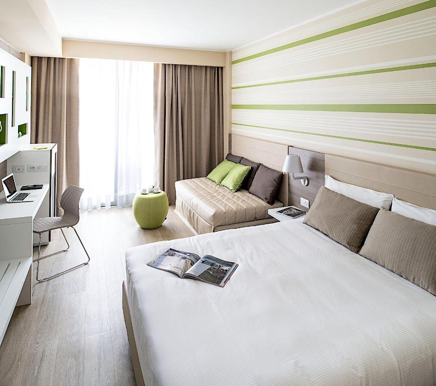 une chambre d'hôtel avec un lit et un canapé dans l'établissement Enjoy Garda Hotel, à Peschiera del Garda