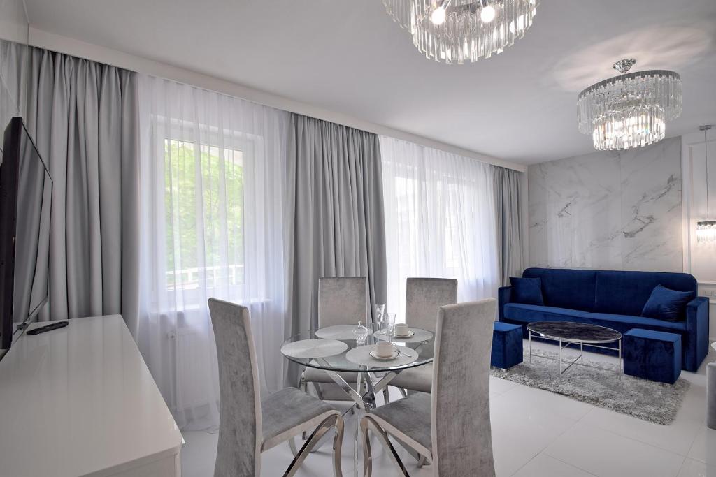 ein Wohnzimmer mit einem Tisch und einem blauen Sofa in der Unterkunft CRYSTAL Apartament 80m od plaży, przy latarni morskiej in Kołobrzeg