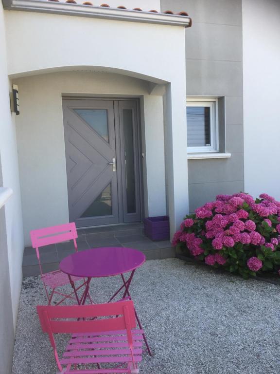 une table rose et une chaise rose devant une maison dans l'établissement Chambre les Hortensias, à Challans