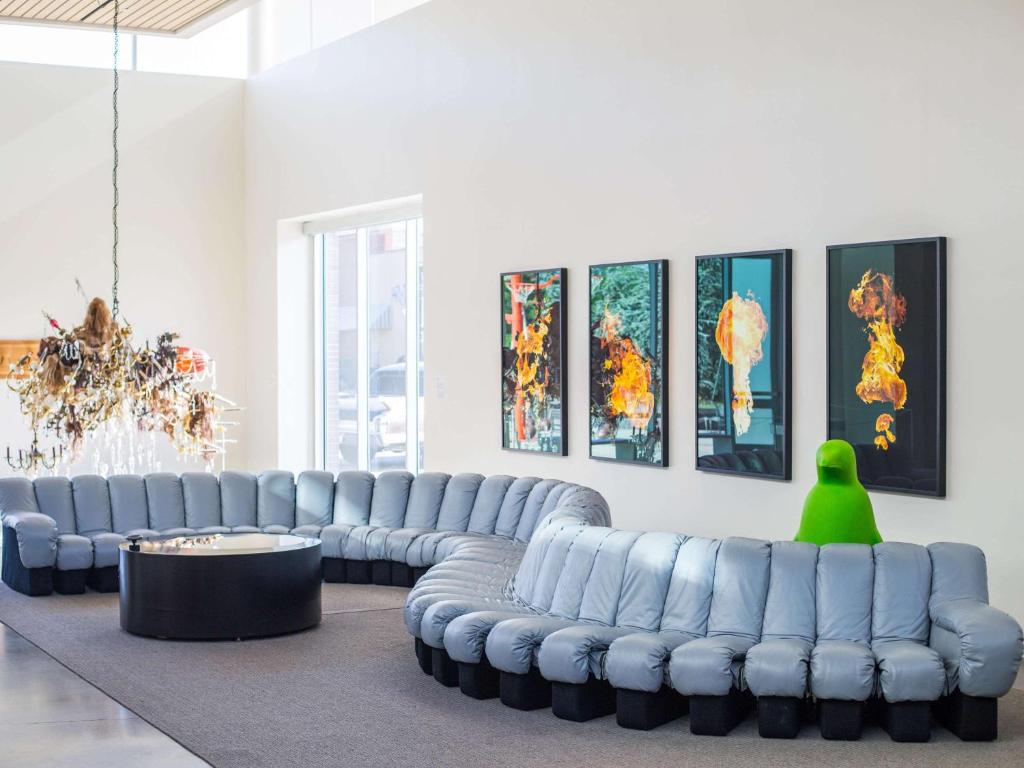 ein Wohnzimmer mit blauen Ledersofas und einer grünen Person in der Unterkunft 21c Museum Hotel Bentonville - MGallery in Bentonville