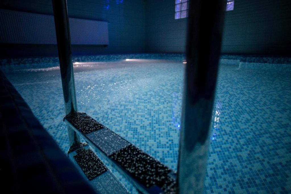 una piscina con suelo de baldosa azul y agua en Hotel Rezydencja Mazury SPA & Lake, en Mrągowo