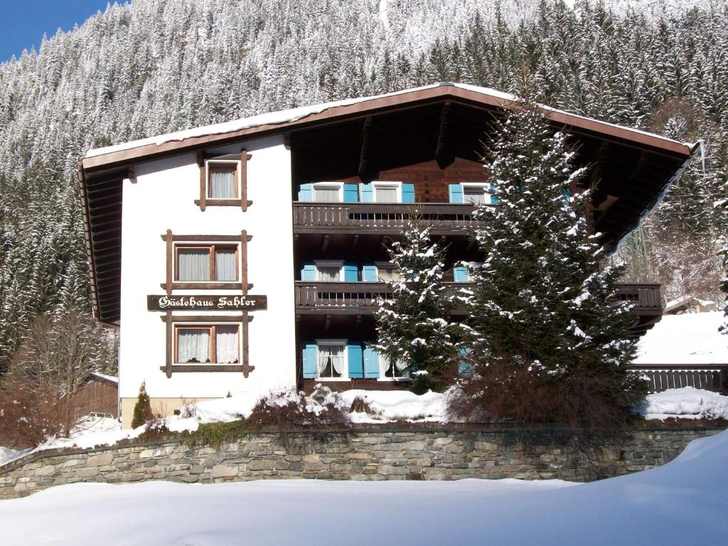 Un edificio nella neve con un albero davanti di Gästehaus Sahler a Gaschurn