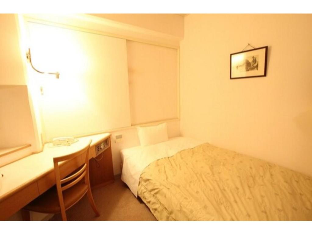 a small bedroom with a bed and a desk and a window at Mizusawa Ground Hotel - Vacation STAY 84945 in Oshu