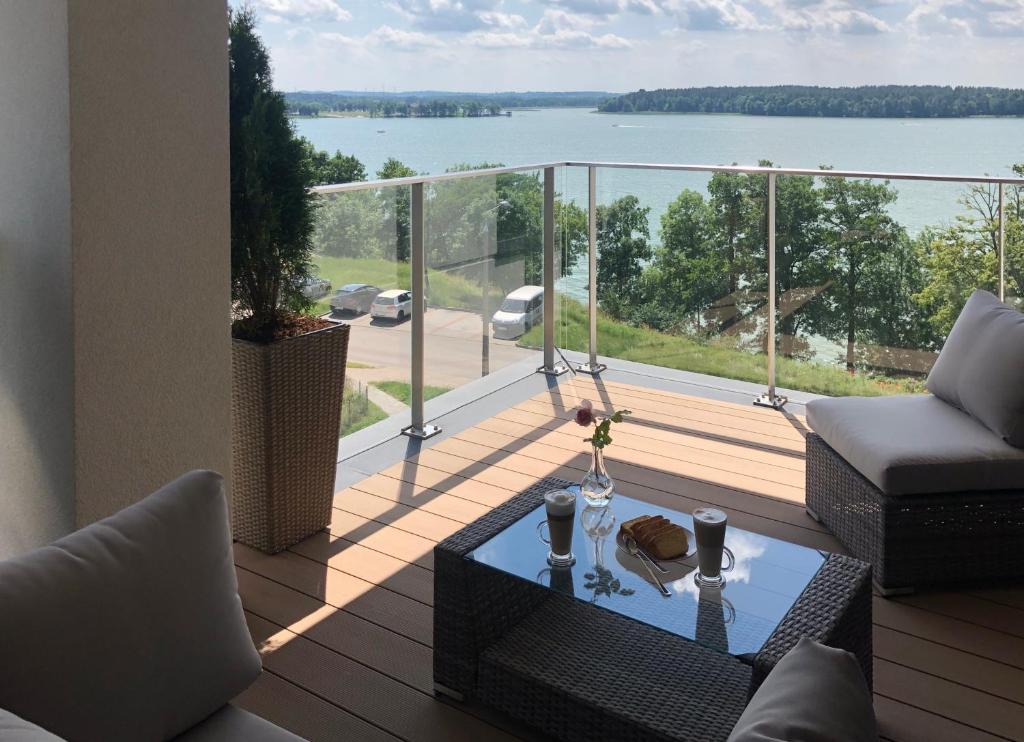 einen Balkon mit einem Tisch und Blick auf das Wasser in der Unterkunft Apartament Złota Brama in Lyck