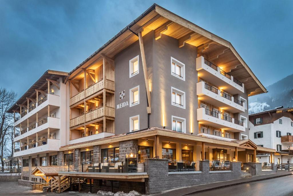 een groot appartementencomplex met veel ramen bij Hotel Meida in Pozza di Fassa