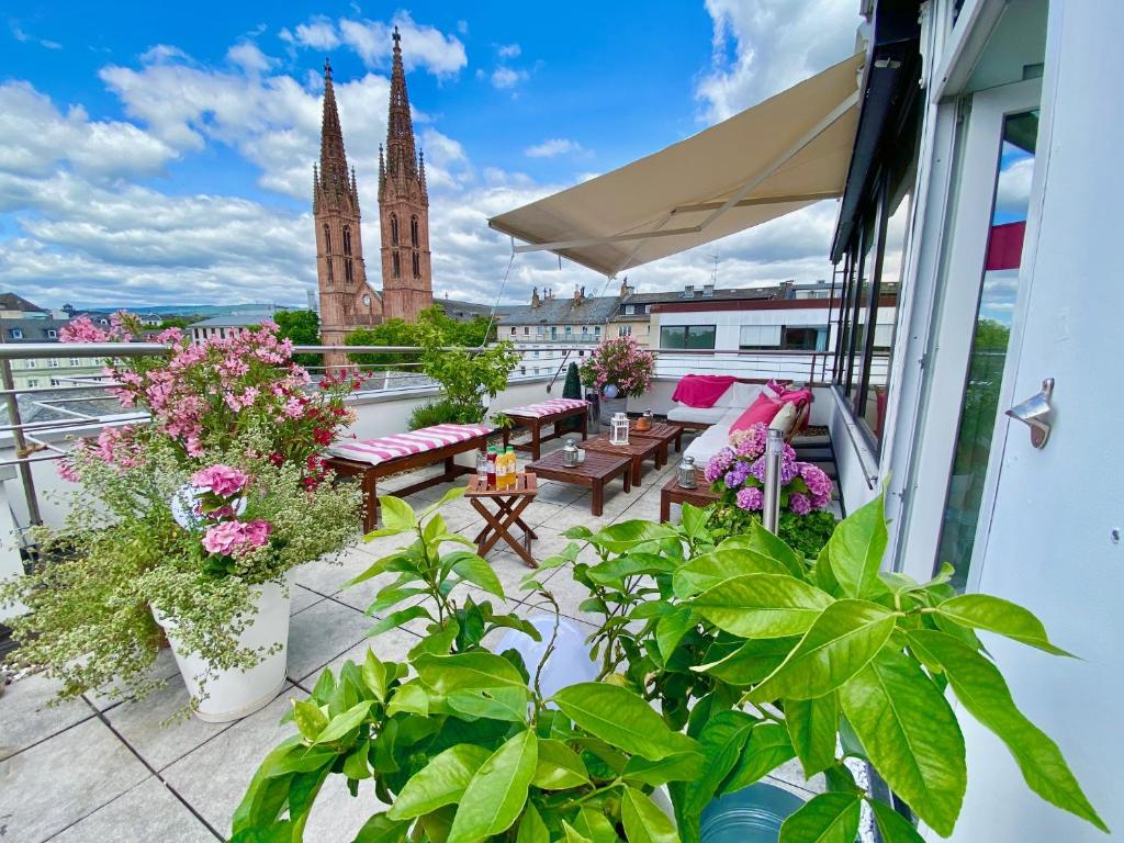 d'un balcon avec des plantes, des tables et une église. dans l'établissement Business Hotel Wiesbaden PRIME, à Wiesbaden