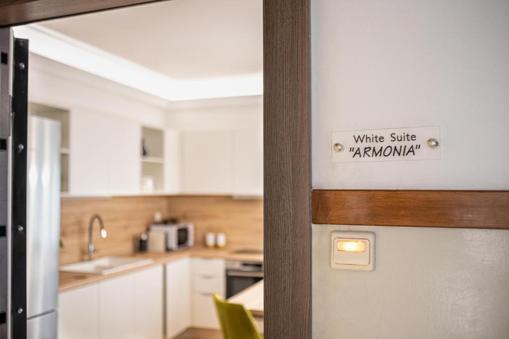 une porte avec un signe indiquant le sourire blanc kanatown dans l'établissement White Suite Armonia, à Thessalonique