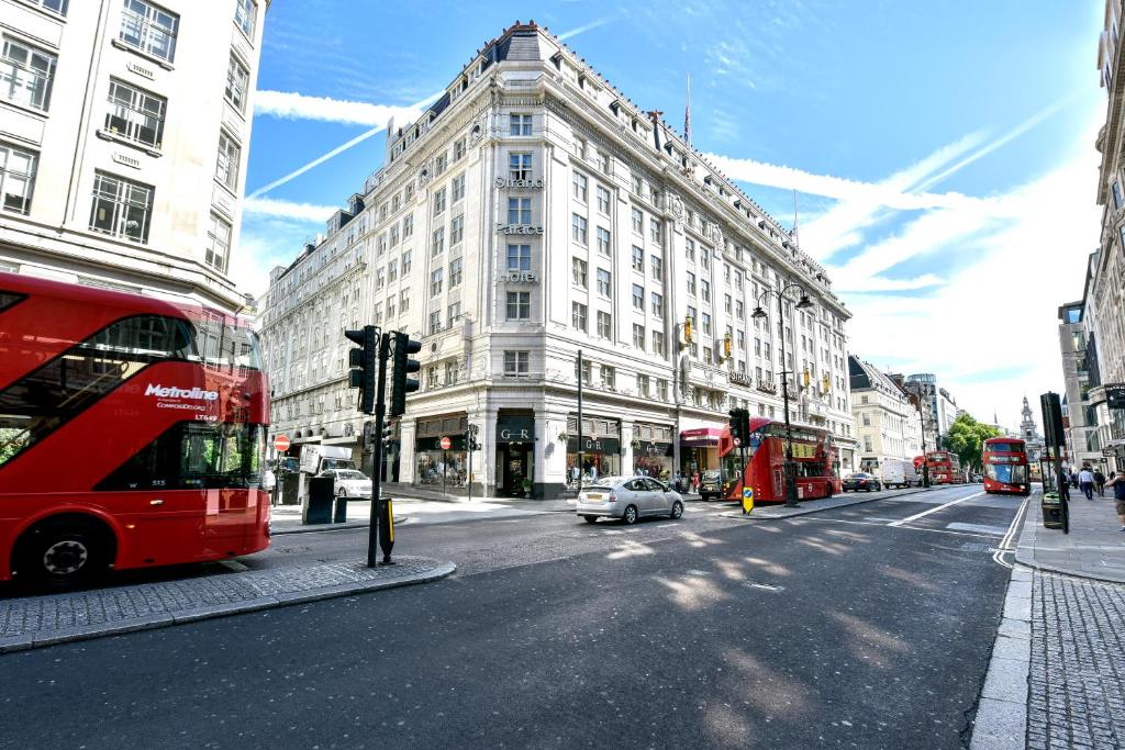 einen roten Doppeldeckerbus, der eine Stadtstraße entlangfährt in der Unterkunft Strand Palace in London