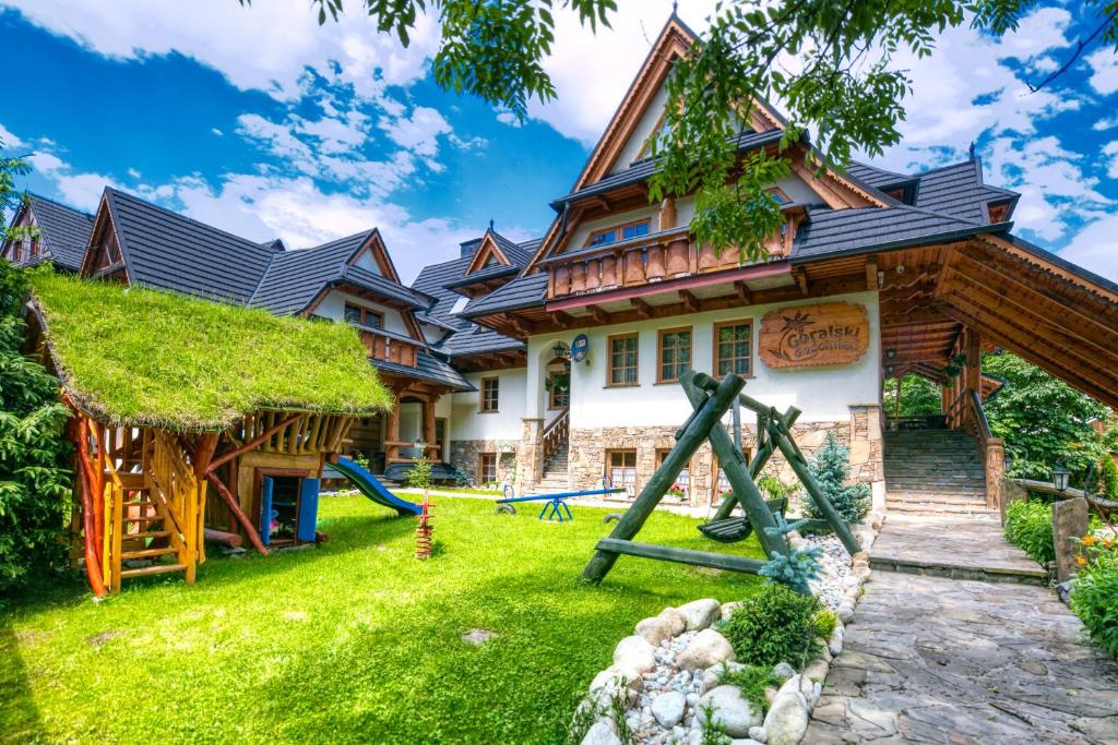 une maison avec une aire de jeux en face dans l'établissement Góralski Gościniec & SPA, à Poronin