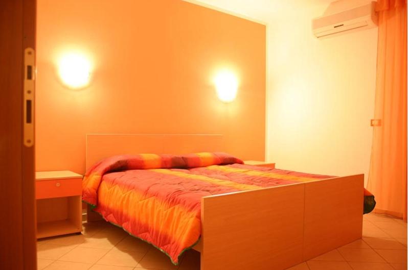 um quarto com uma cama com um edredão laranja em L'Arcobaleno em Santa Maria la Palma