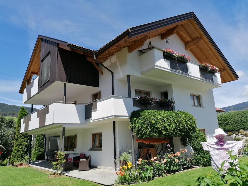 ein weißes Haus mit Blumen davor in der Unterkunft Appartements Oberleiter in Olang