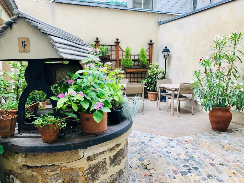 um pátio com vasos de plantas e uma mesa e cadeiras em Amiral-Fondary em Paris