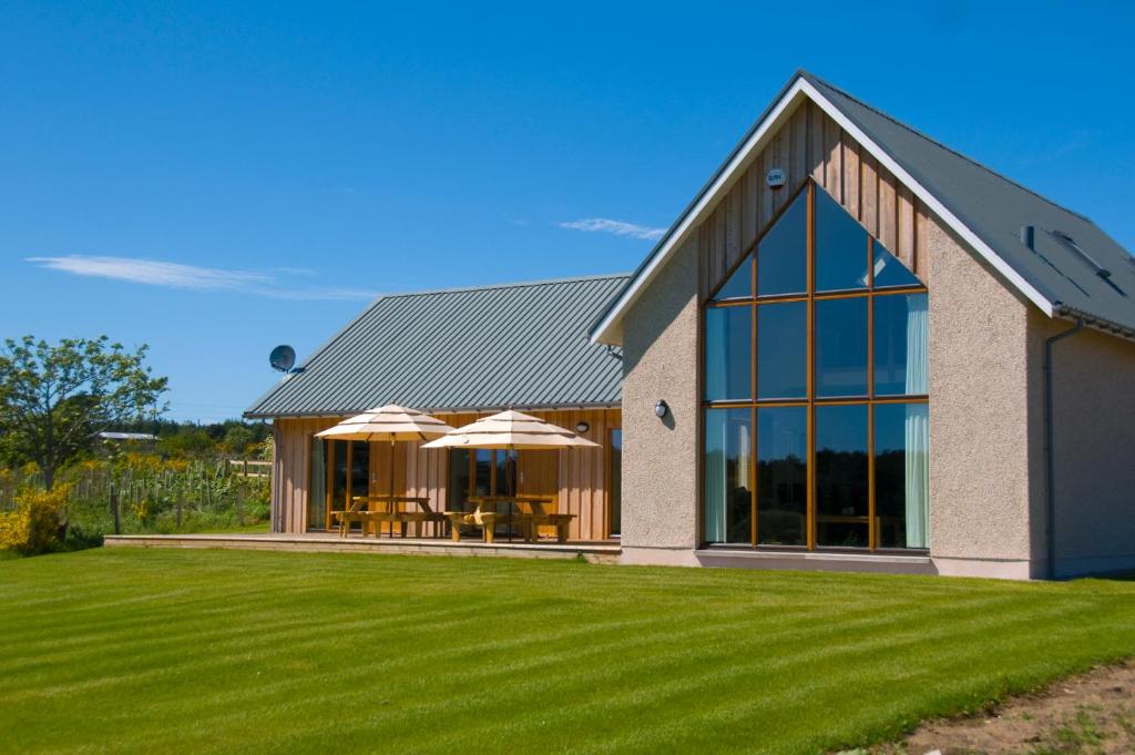 une grande maison avec une pelouse dans l'établissement Clovenstone Lodges, à Inverurie