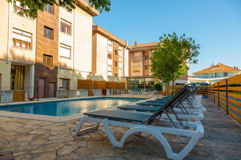 uma fila de espreguiçadeiras junto a uma piscina em Apartamentos Los Arces em Isla