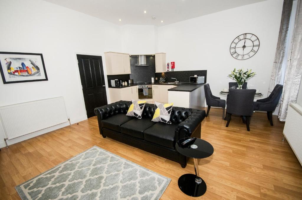 sala de estar con sofá negro y cocina en Parkhill Luxury Serviced Apartments - City Centre Apartments, en Aberdeen