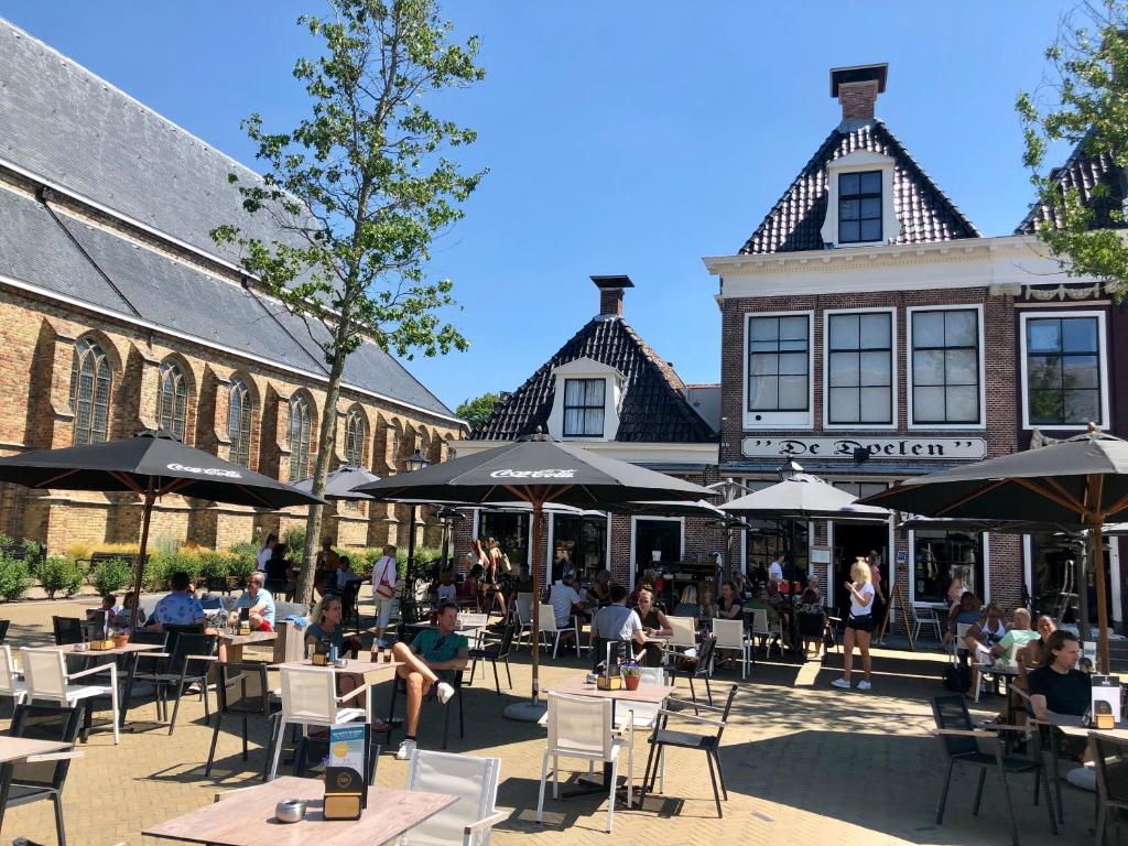 een groep mensen die aan tafels voor een gebouw zitten bij Hotel Grandcafe De Doelen in Franeker