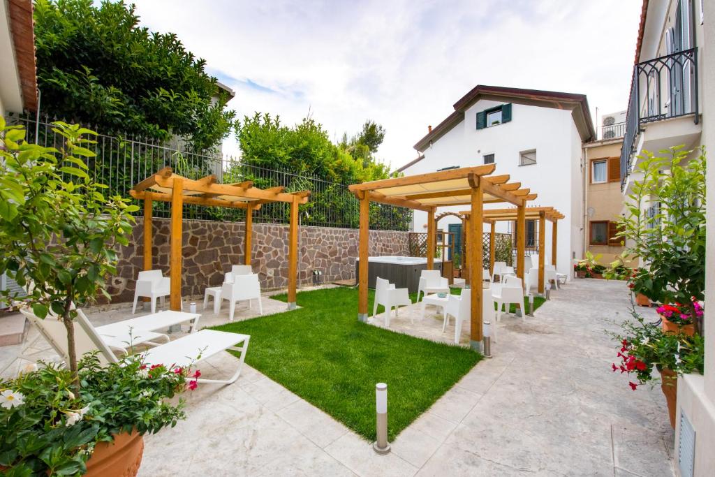 een tuin met een houten pergola en witte stoelen bij Ravello House in Ravello