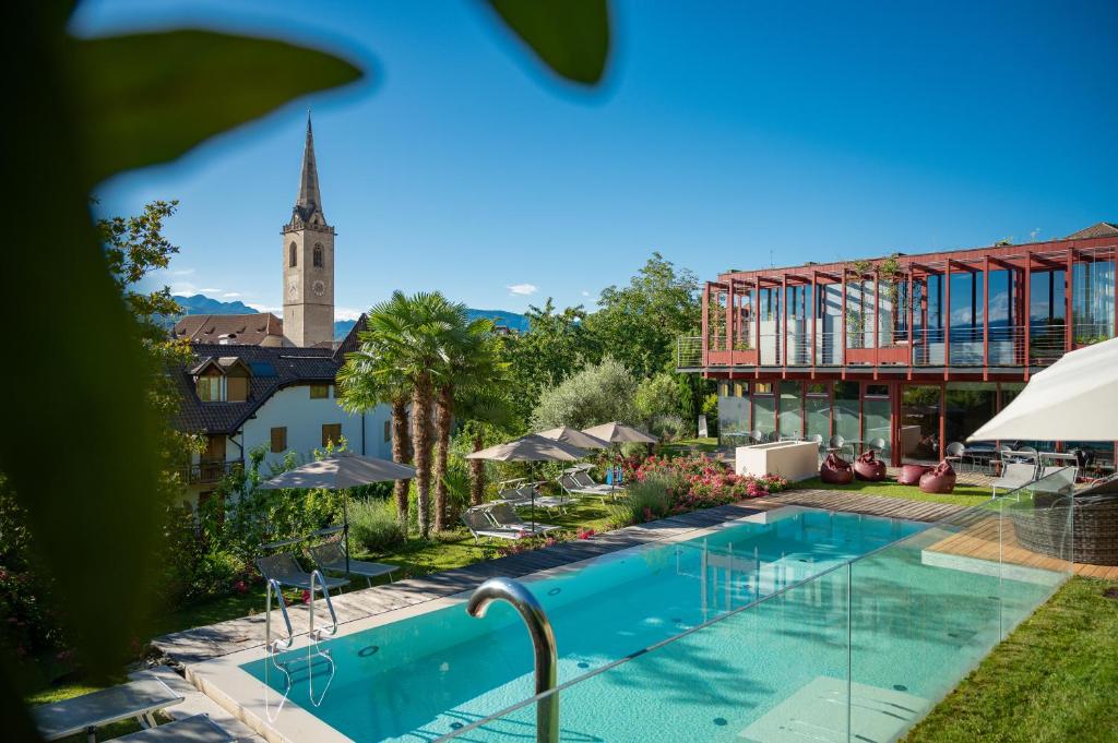 a view of the pool at a resort with a church at Hotel Goldener Stern in Caldaro