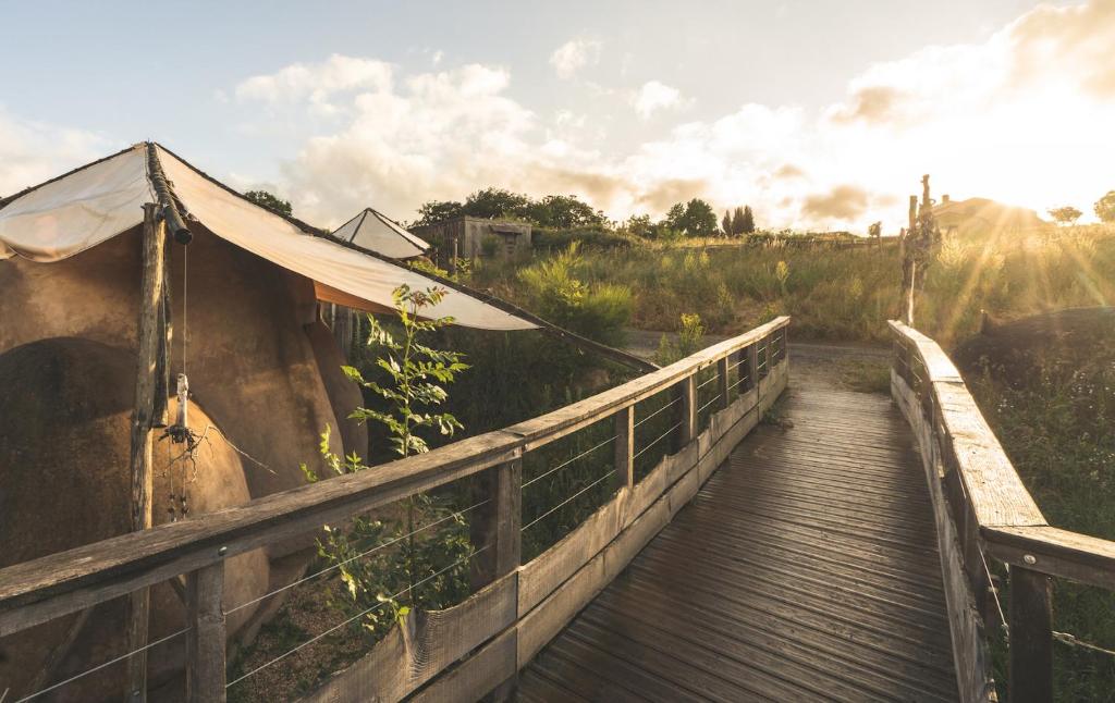 einen hölzernen Gehweg mit einem Zelt auf einer Brücke in der Unterkunft Terragora Lodges - Hébergement atypique in Les Épesses