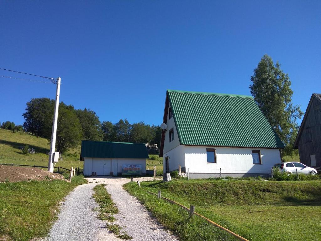 Casa blanca con techo verde y camino de grava en Rooms Apartment Durmitor, en Žabljak