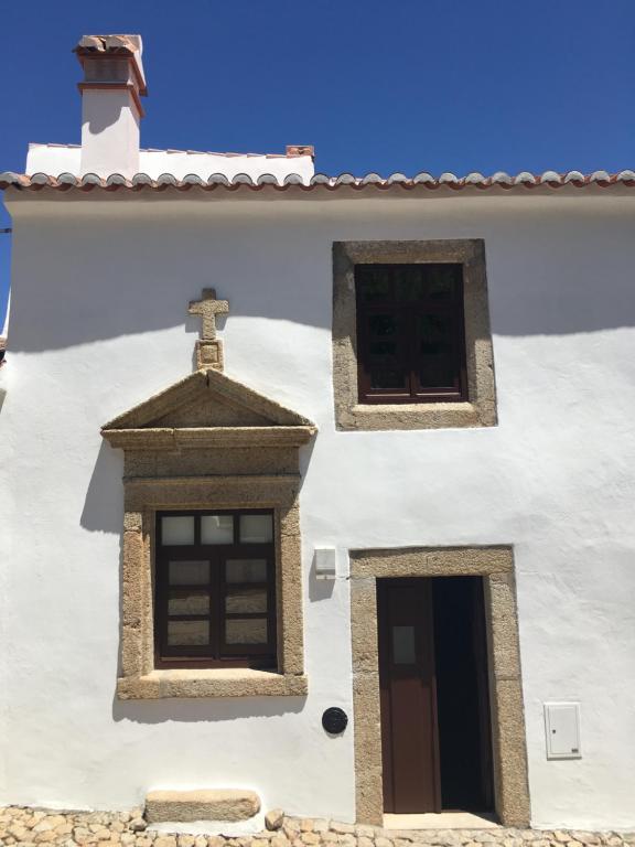 um edifício branco com duas janelas e uma cruz em Casa do Sétimo Passo em Marvão