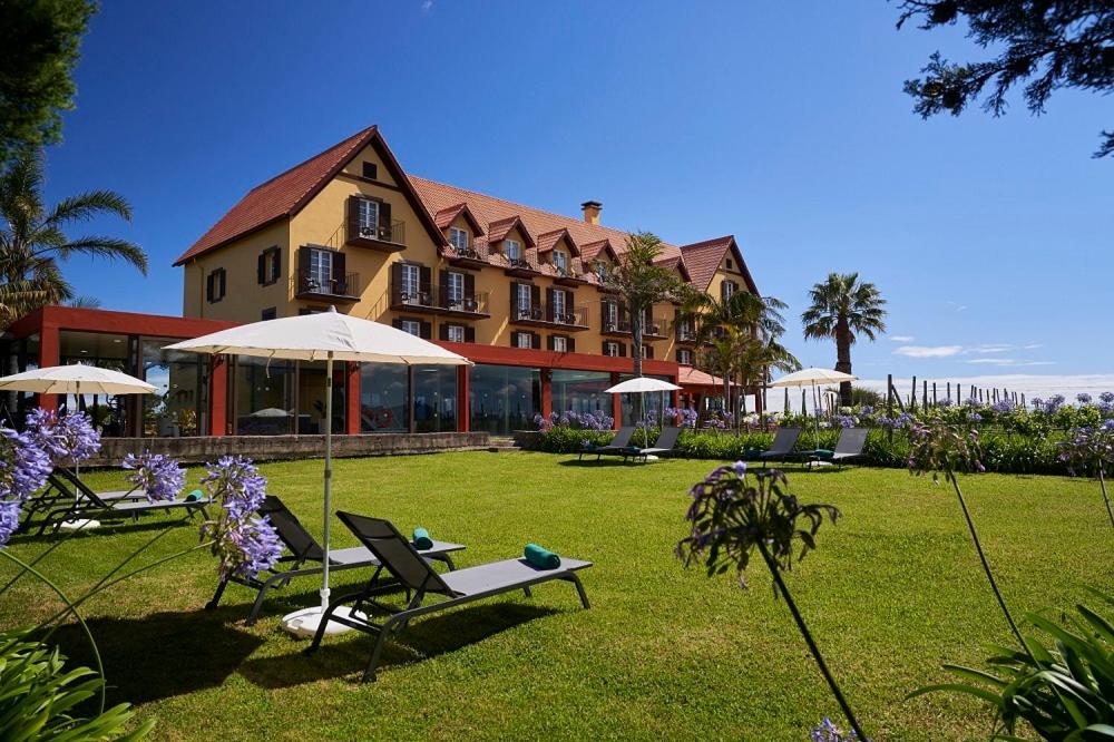 un grande edificio con sedie e ombrelloni in un cortile di Hotel Quinta Do Furao a Santana