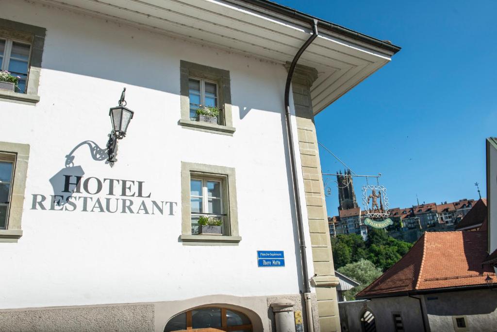 um sinal para um restaurante de hotel ao lado de um edifício em Le Sauvage em Fribourg