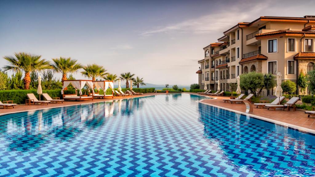 ein großer Pool mit Stühlen und Gebäuden in der Unterkunft Burgas Beach Resort Apartments in Burgas City