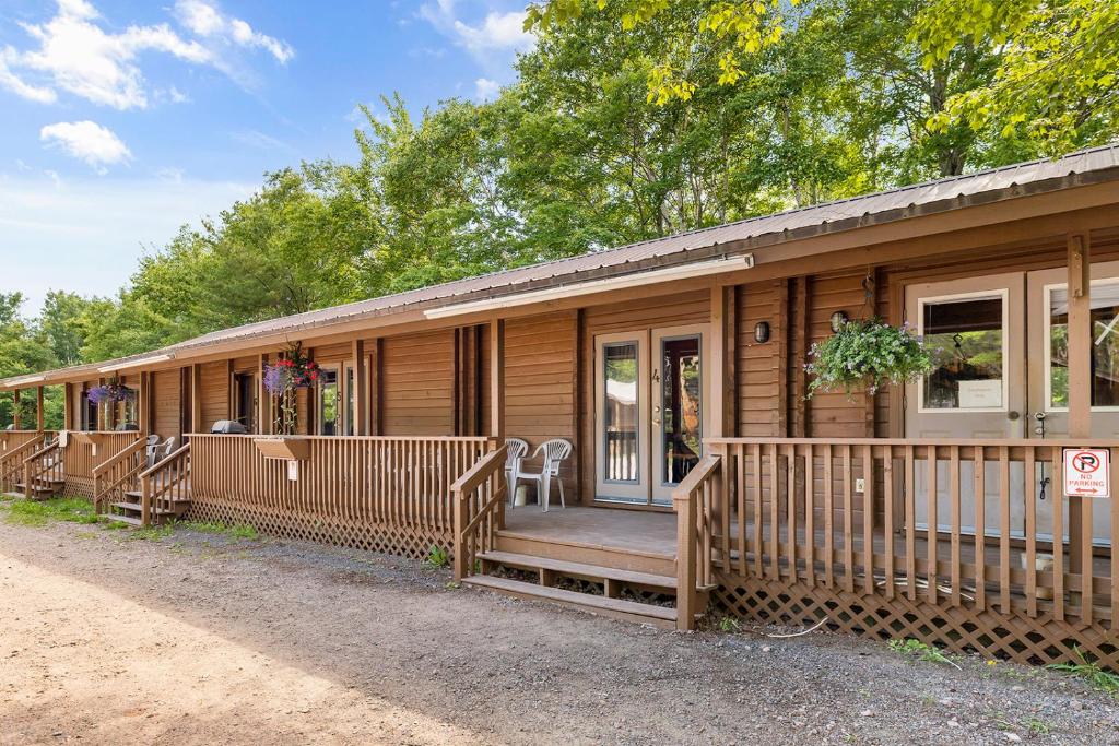 een houten huis met een veranda en een terras bij Ingonish Chalets in Ingonish Beach