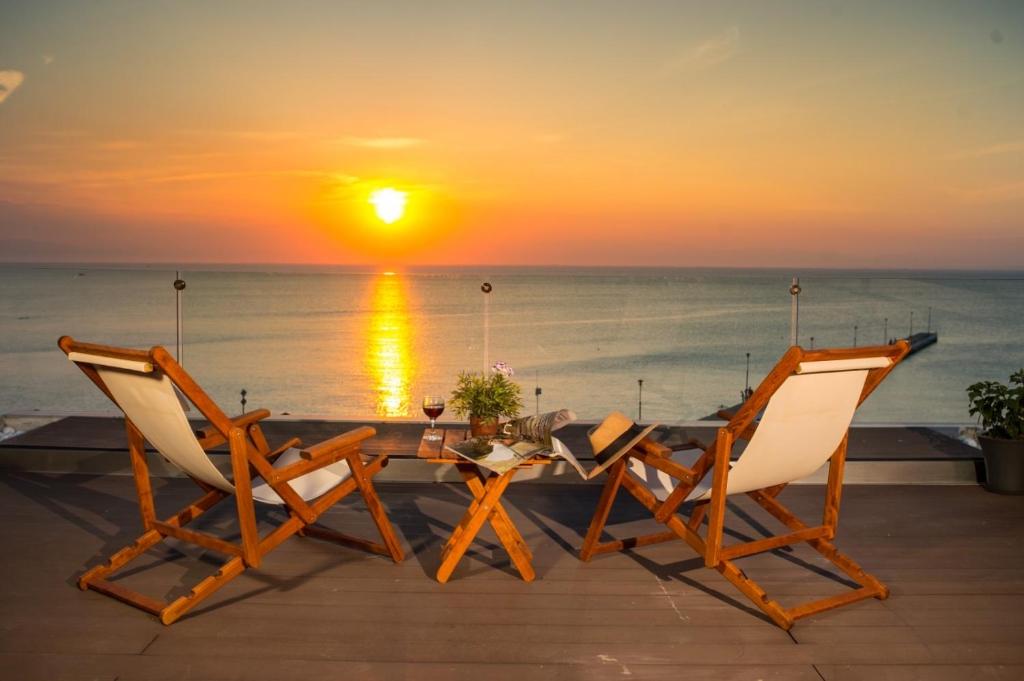 a table and two chairs with a sunset in the background at Vento di Mare in Perea