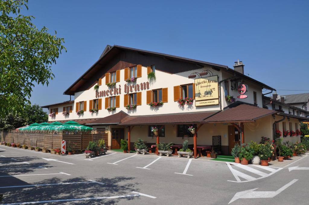 a building with a parking lot in front of it at Penzion Kmečki Hram in Ljubljana