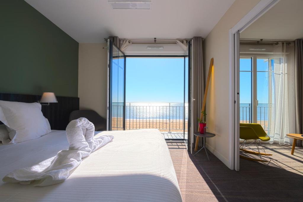 een slaapkamer met een groot bed en een balkon bij Les Flots - Hôtel et Restaurant face à l'océan - Châtelaillon-Plage in Châtelaillon-Plage