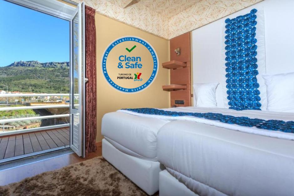 um quarto de hotel com uma cama e uma varanda em Sever Rio Hotel em Marvão