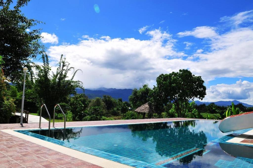 une piscine avec des montagnes en arrière-plan dans l'établissement KuadKhonThoe Pai Cottage, à Pai